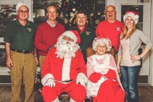 Lions (from left) Bill Muensch, Joe Marquedant, Don Cronin, Bob Chesmore and Christine Curren stand behind the Sullivans as Santa and Mrs. Claus.
