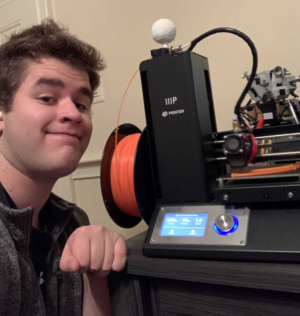 Hopkinton High School senior Tyler Rhodes poses with his 3D printer